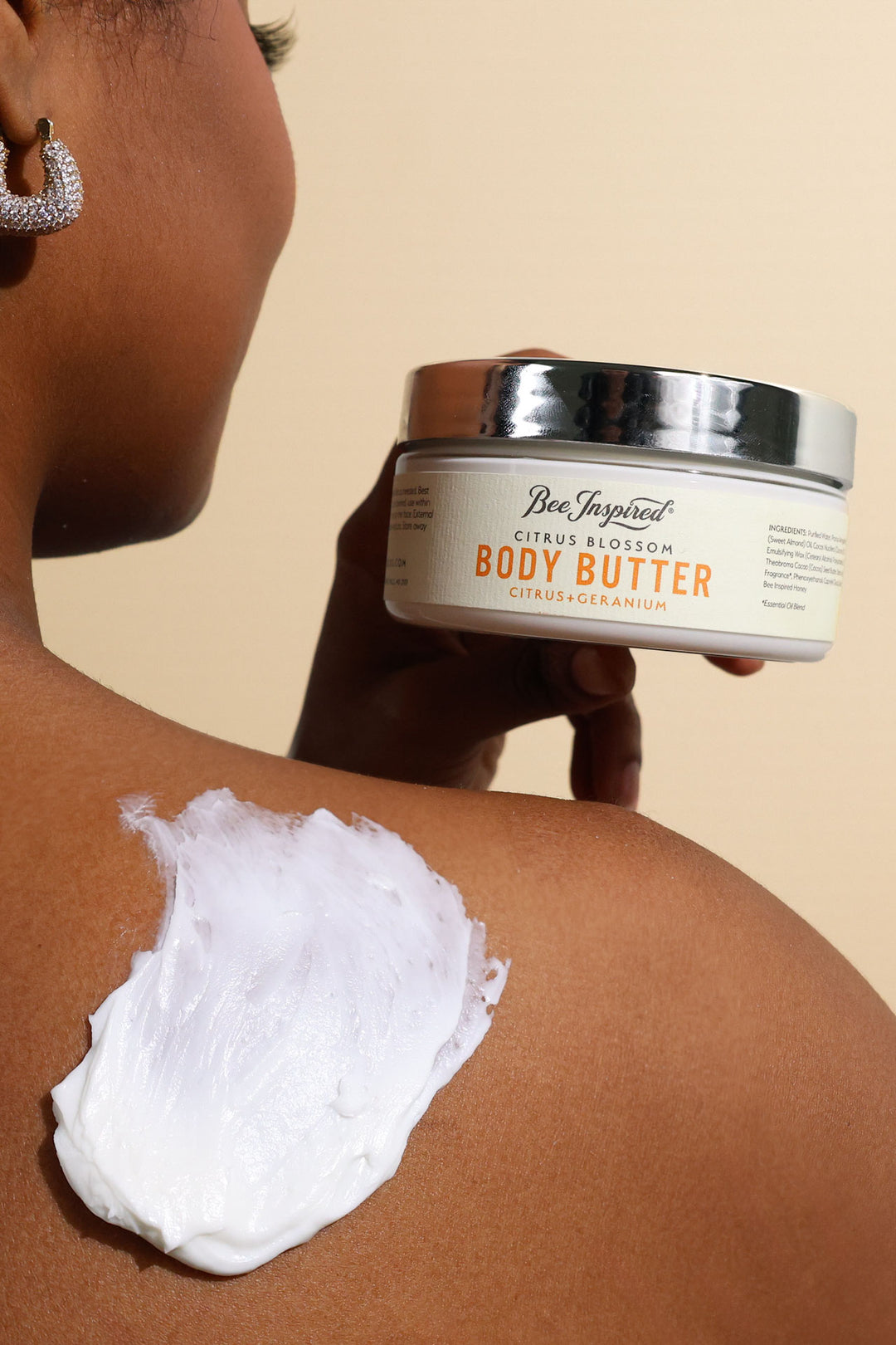 A woman using Citrus Blossom body butter on her shoulder