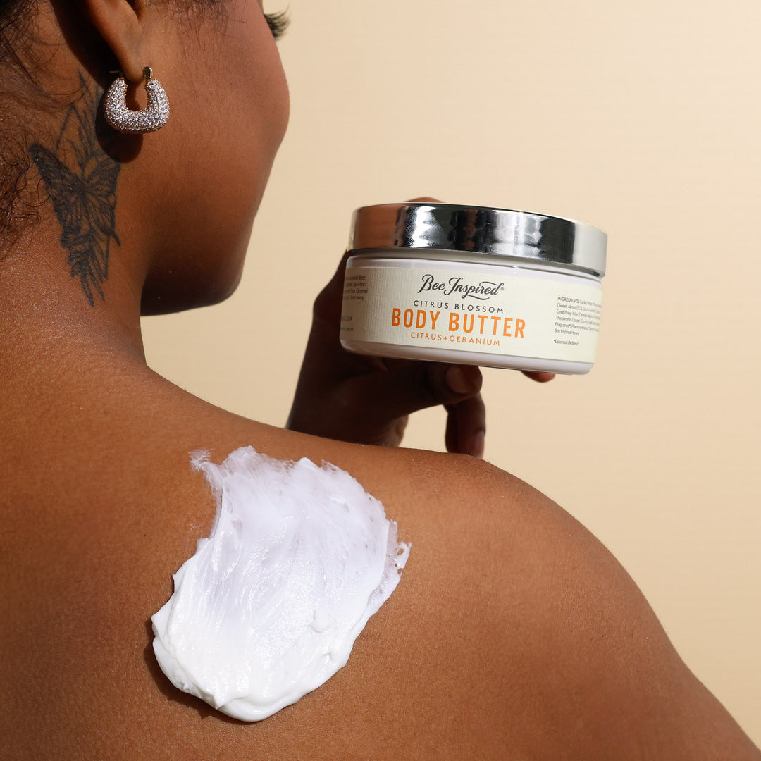 A woman using Citrus Blossom body butter on her shoulder