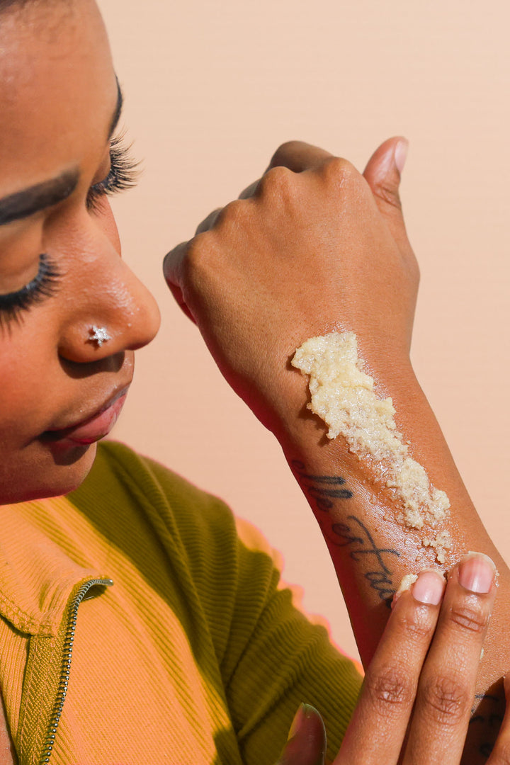 A woman using Citrus Blossom body scrub on her arm