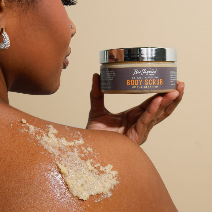 A woman using Citrus Blossom body scrub on her shoulder