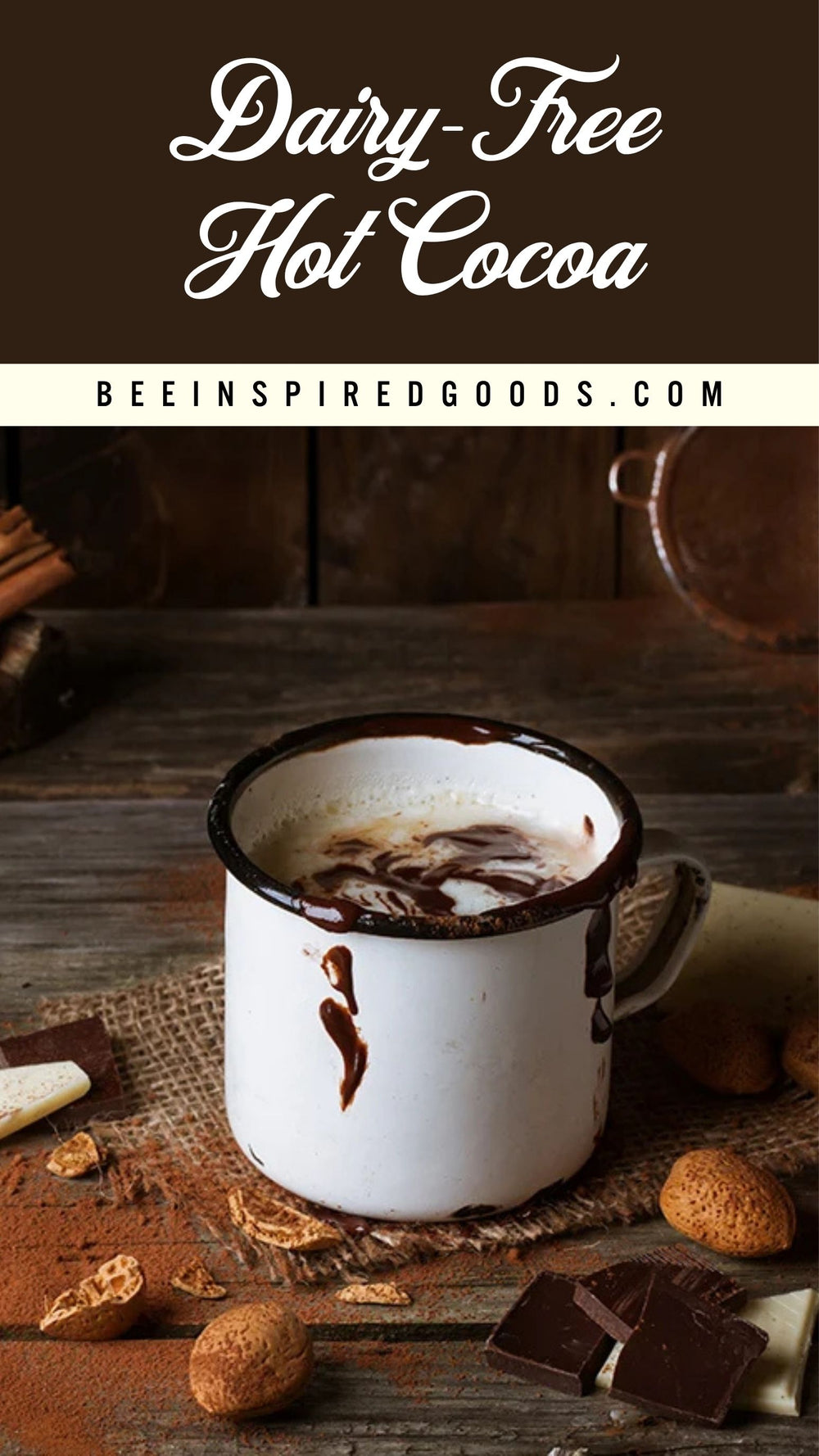 A white enamel mug filled with dairy-free hot cocoa, set on a rustic wooden table with chocolate pieces, nuts, and cinnamon sticks. The top of the image features a dark brown banner with the text 'Dairy-Free Hot Cocoa' and 'BEEINSPIREDGOODS.