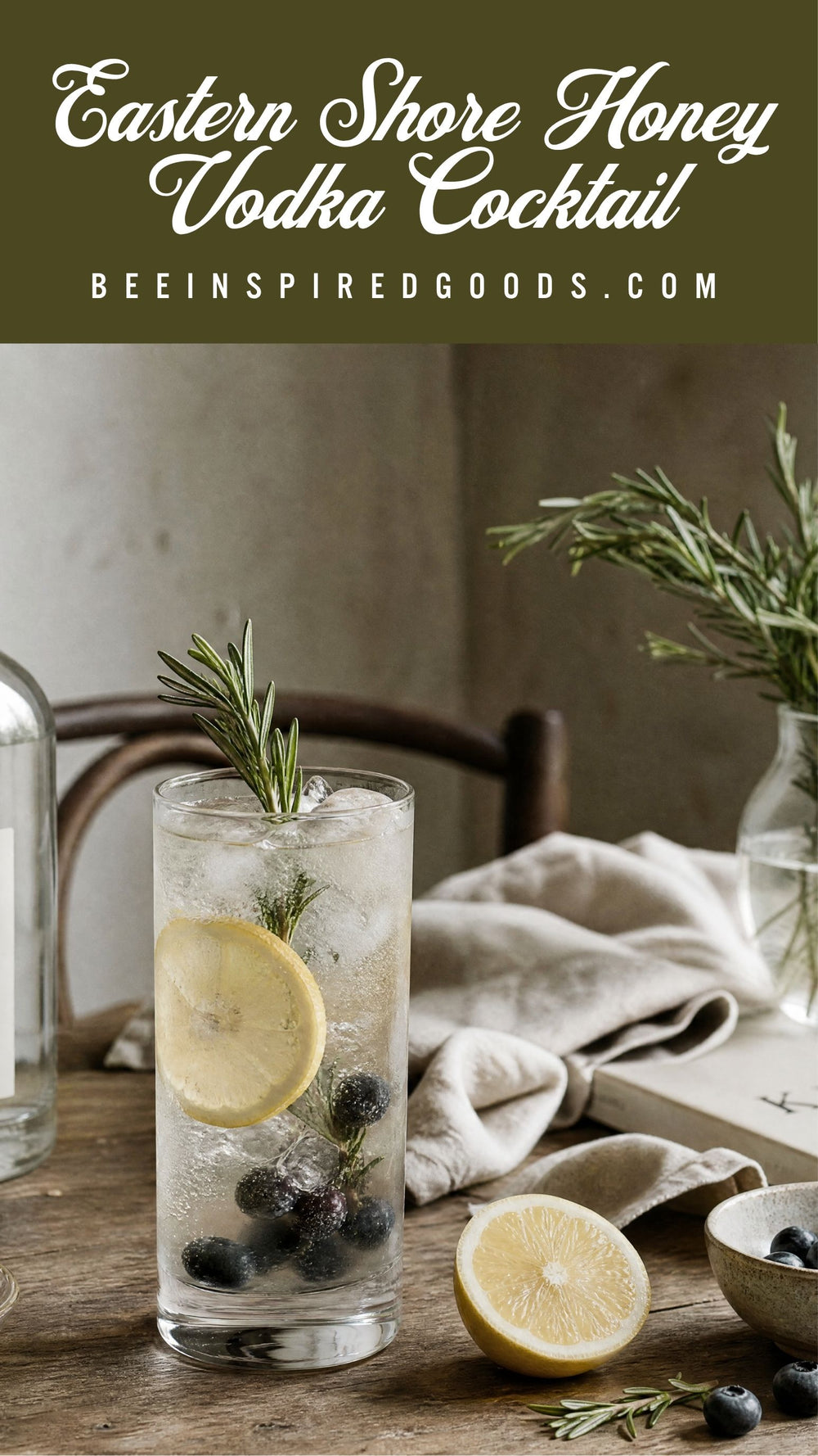 A tall clear glass filled with a clear cocktail, ice, a lemon slice, blueberries, and a rosemary sprig, set on a rustic wooden table with a folded linen cloth, a lemon half, and a small bowl of blueberries. White text at the top reads 'Eastern Shore Honey Vodka Cocktail' and 'BEEINSPIREDGOODS.