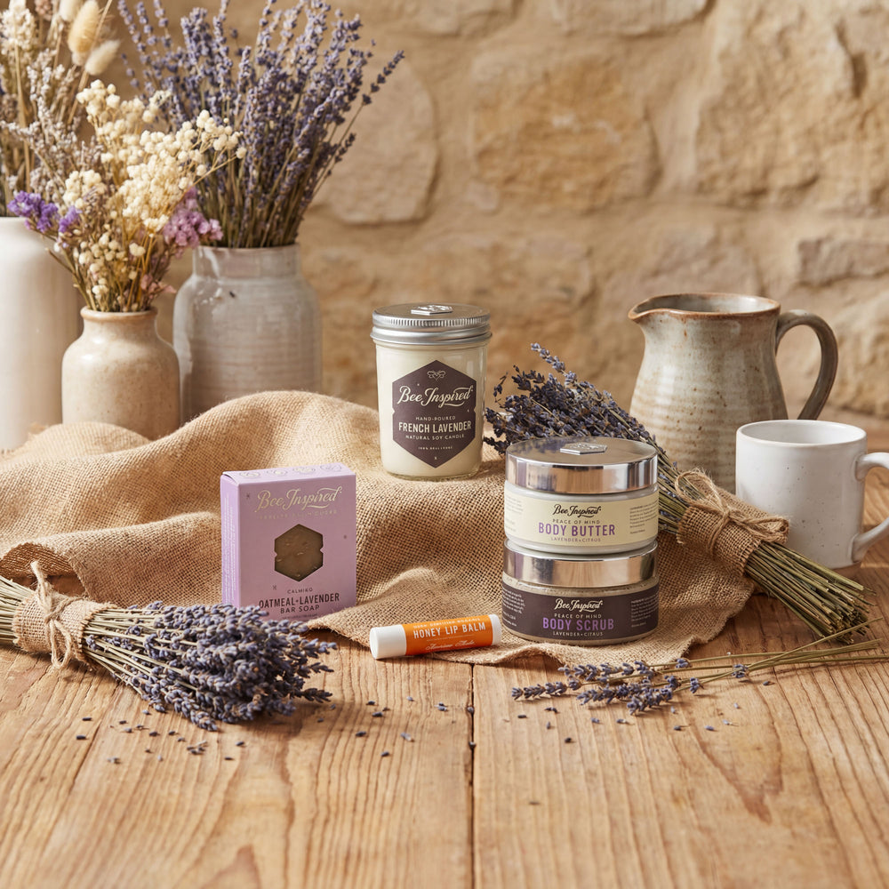 Cosmetic products with lavender on a wooden table against a stone wall.