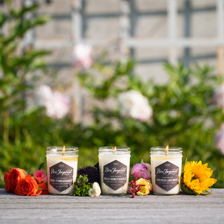 Garden jelly jar candle set burning next to flowers 