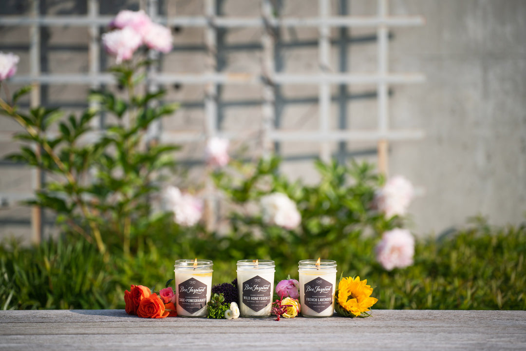 Garden jelly jar candle set burning next to flowers 