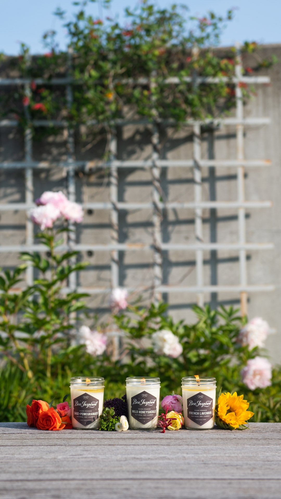 Garden jelly jar candle set burning next to flowers 