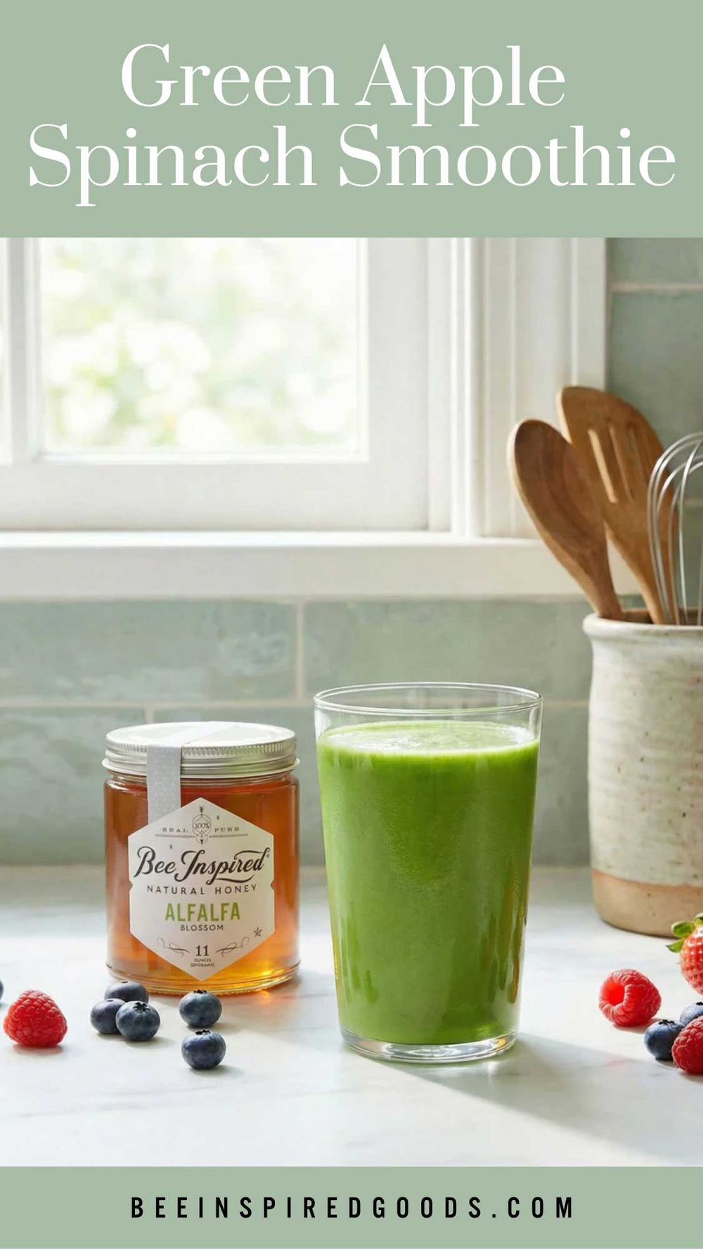 Green apple spinach smoothie in a glass with a jar of honey and fresh fruits on a kitchen counter.