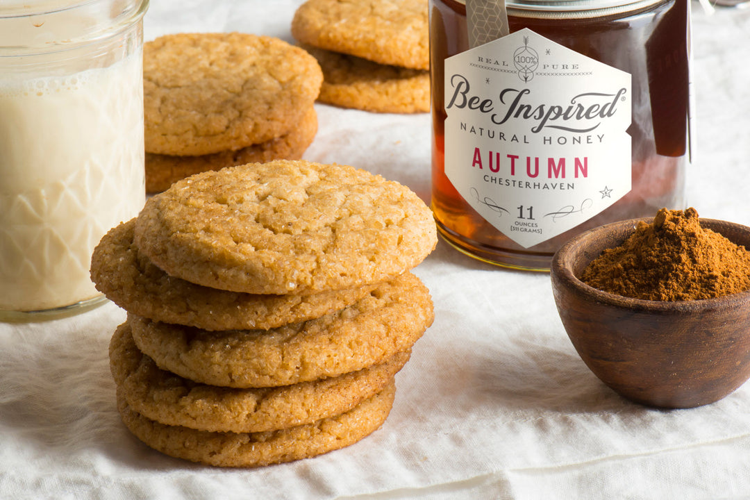 cookies next to a glass of milk, a bowl of ground cinnamon, and a jar of autumn honey from bee inspired honey retail store in owings mills