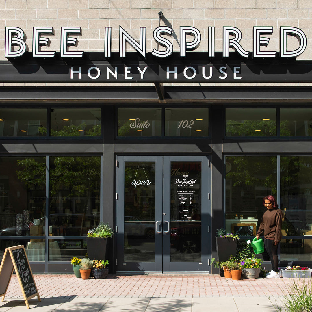 Main entrance of Bee Inspired Honey House with a woman watering flowers 