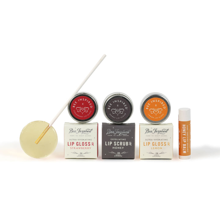 Collection of lip care products including lip glosses, scrubs, and a stick on a white background.