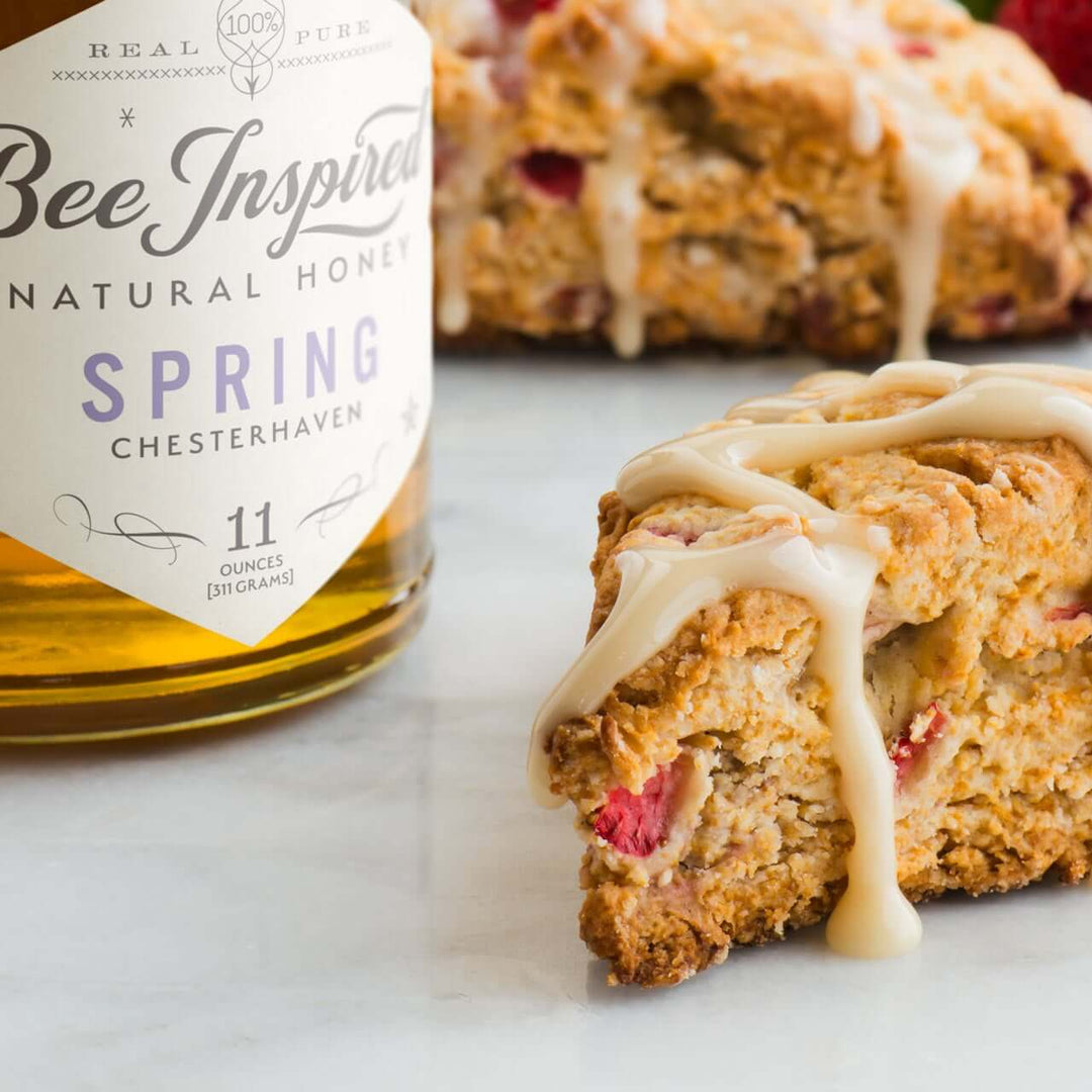 Bee Inspired Spring Honey next to a strawberry scone topped with icing