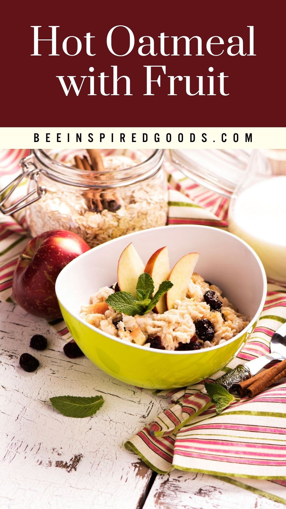 A bowl of hot oatmeal with fruit, including apple slices, blueberries, and mint, served on a rustic white wooden table with a striped napkin, a jar of oats, and a red apple. The top of the image features a dark red banner with the text 'Hot Oatmeal with Fruit' and 'BEEINSPIREDGOODS.