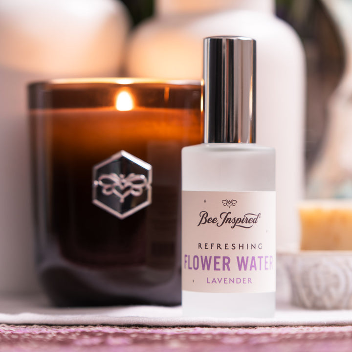 Bottle of 'Bee Inspired' lavender flower water with a candle in the background