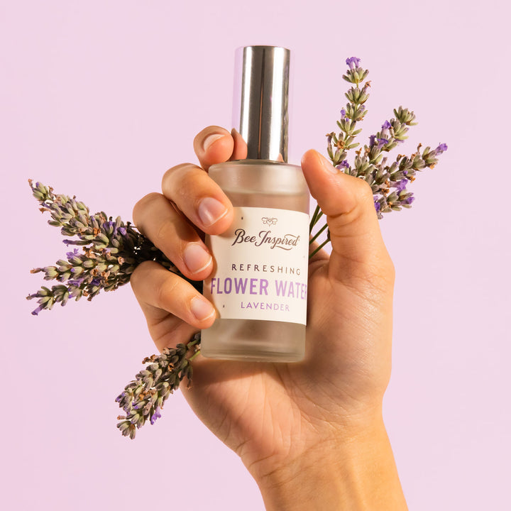 hand holding stems of lavender and lavender flower water