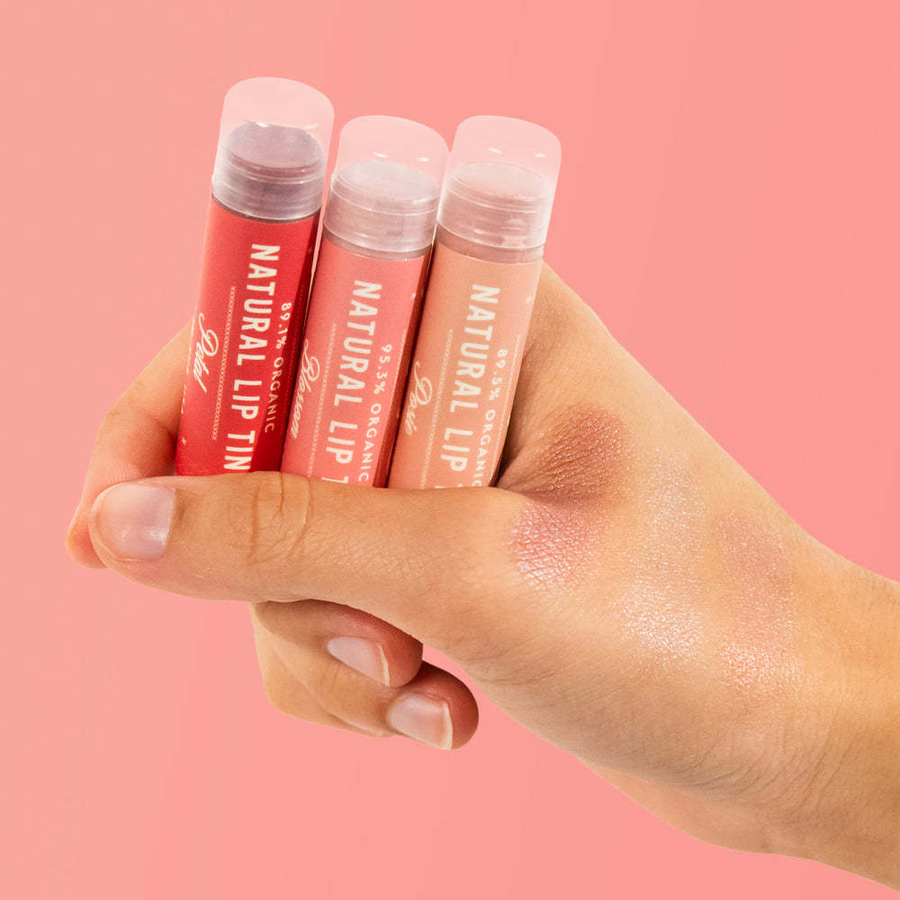 holding Naturals lip tint trio with colors tested on hand