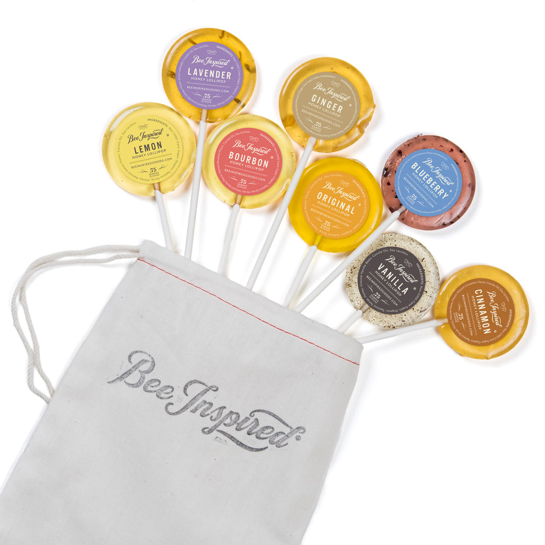 Assorted lollipops with visible flavors and a 'Bee Inspired' drawstring bag on a white background