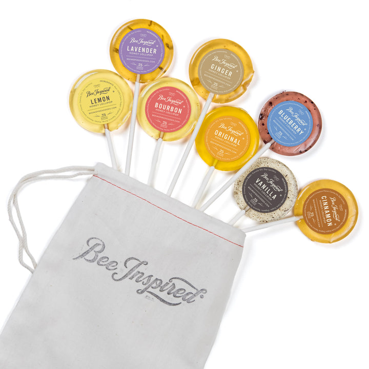Assorted lollipops with visible flavors and a 'Bee Inspired' drawstring bag on a white background