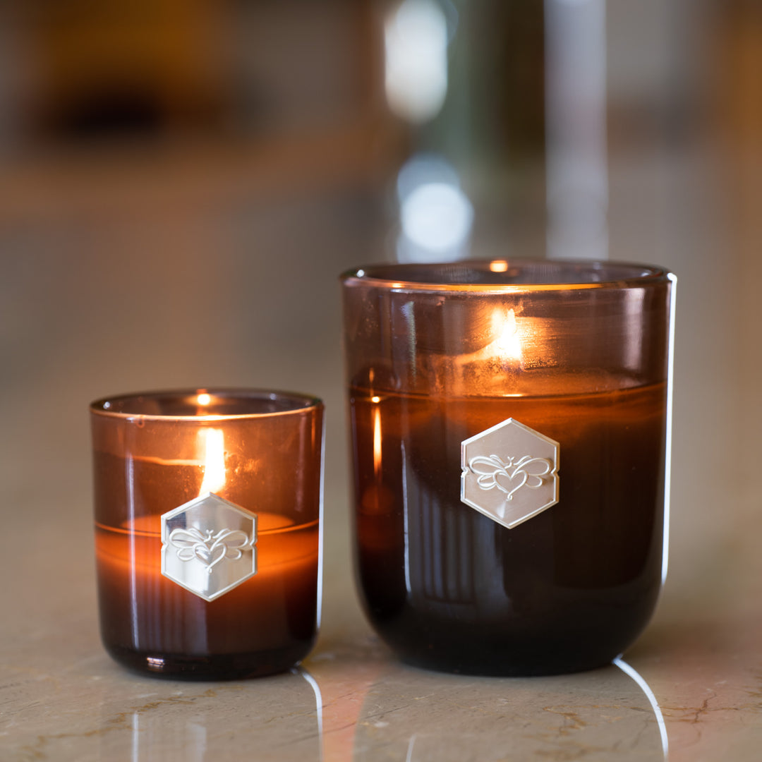 A small candle and a luxe candle burn next to each other 