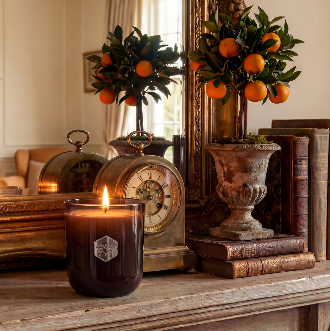 Candle with a decorative clock and books on a wooden surface
