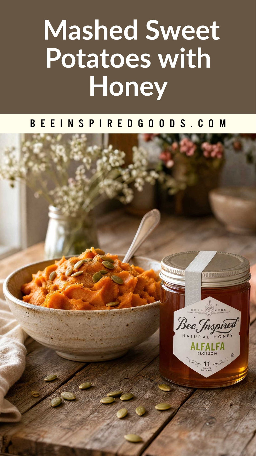 A bowl of mashed sweet potatoes topped with pumpkin seeds sits on a rustic wooden table next to a jar of Bee Inspired Goods Alfalfa Natural Raw Honey. The background features a soft-focus floral arrangement and a dark brown banner at the top with the text 'Mashed Sweet Potatoes with Honey' and 'BEEINSPIREDGOODS.