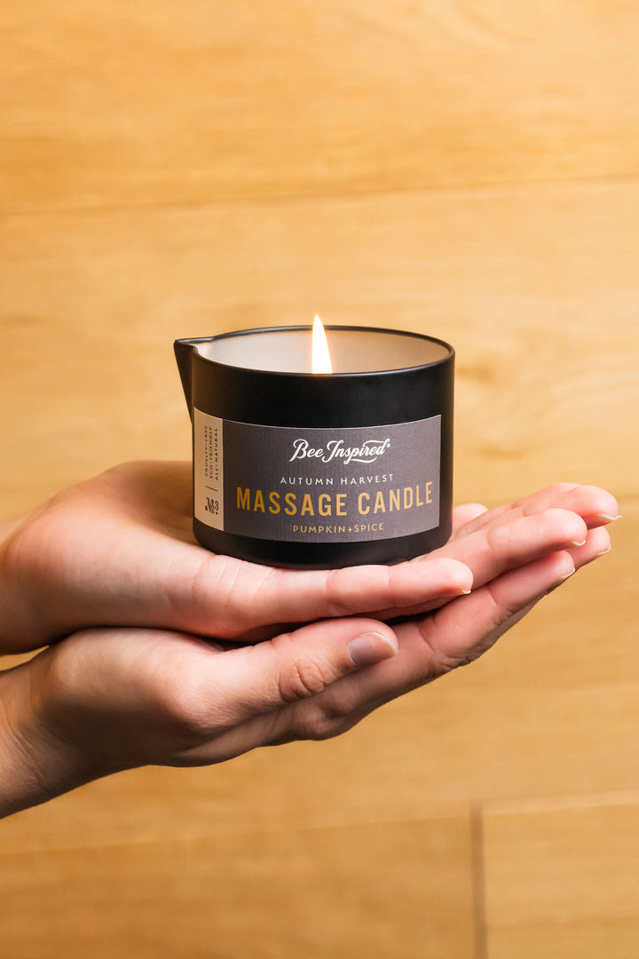 hands holding a lit autumn harvest massage candle