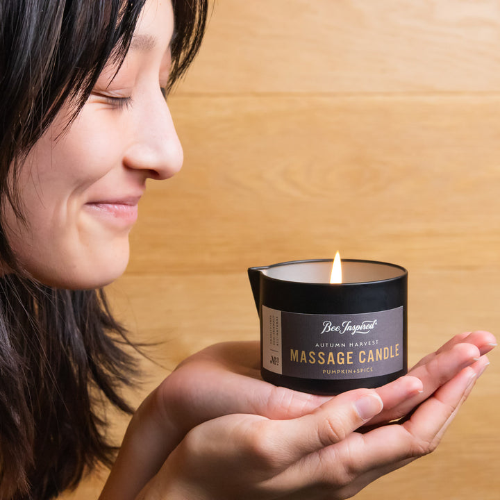 woman holding a lit autumn harvest massage candle