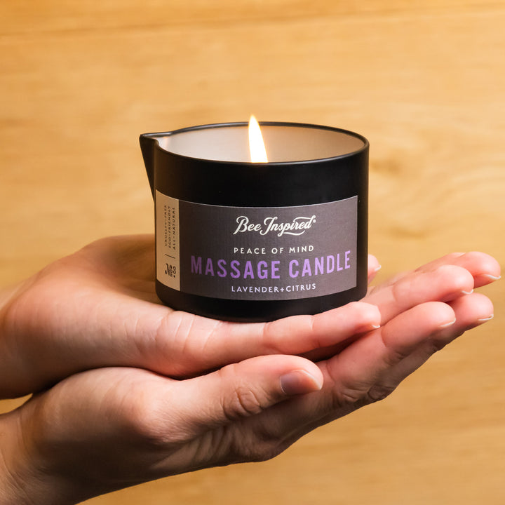 hands holding a lit peace of mind massage candle