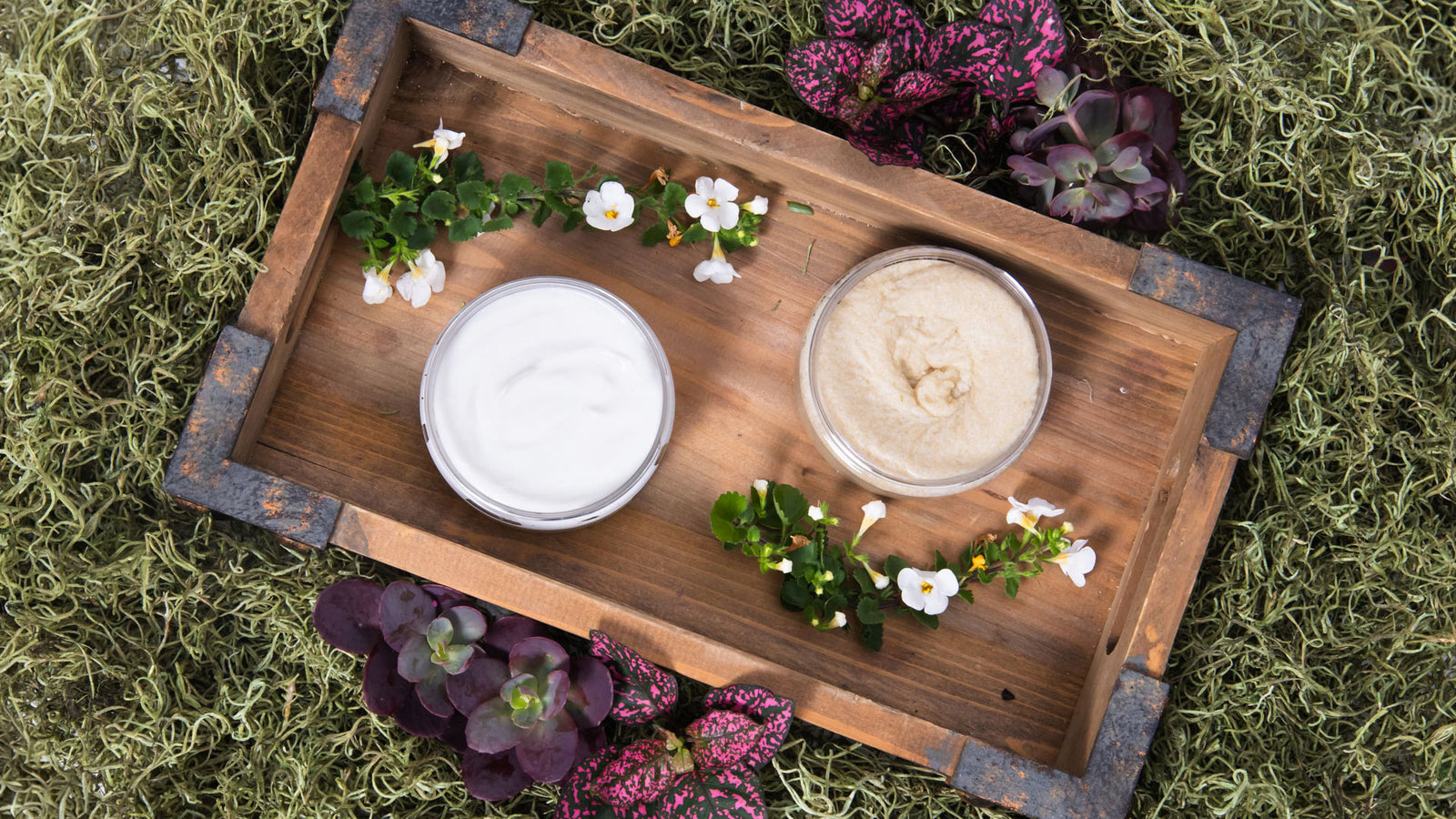 bee inspired nectar + honey body butter and body scrub on a tray in grass