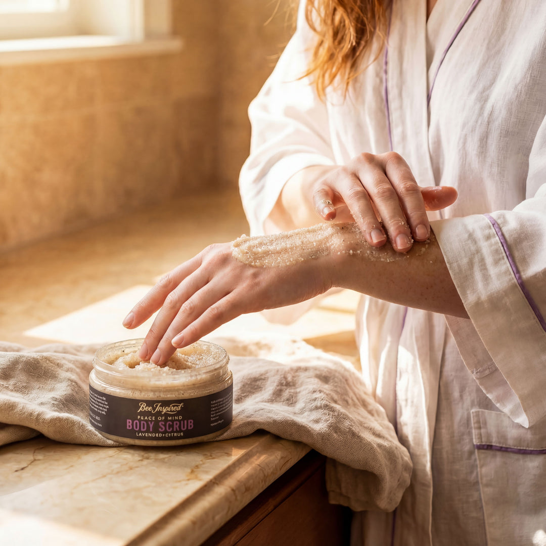 Person applying body scrub to their arm with a jar of body scrub on a wooden surface.