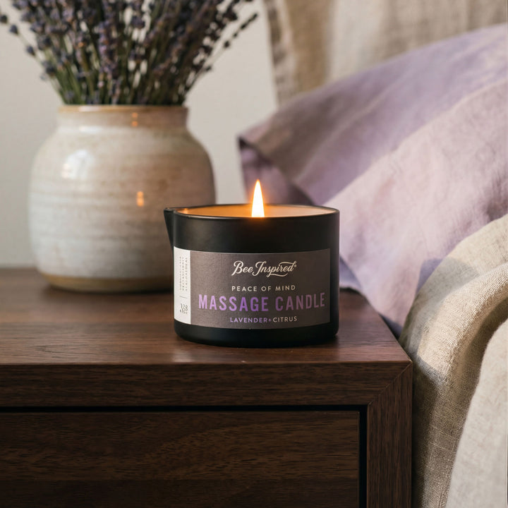 Massage candle labeled 'Peace of Mind' on a wooden surface with lavender in the background