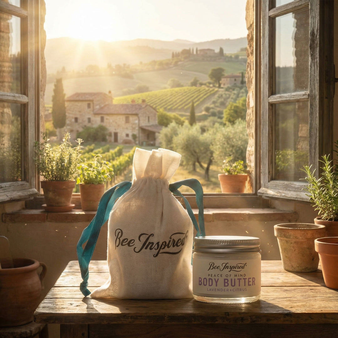 Bee Inspired body butter jar and drawstring bag on a wooden table with a scenic window view.