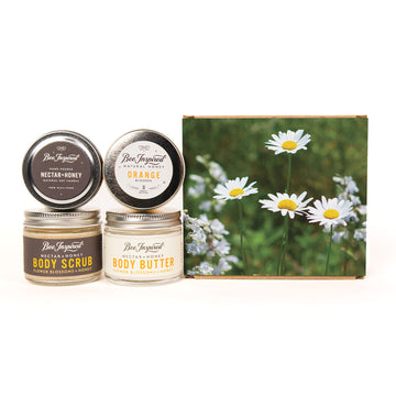 Three jars of Ben Trujillo Natural Products body care products and a matching gift box featuring daisies. The set includes Nectar-Honey body scrub, Orange blossom body butter, and a body scrub with beeswax and honeycomb, all arranged on a white background.