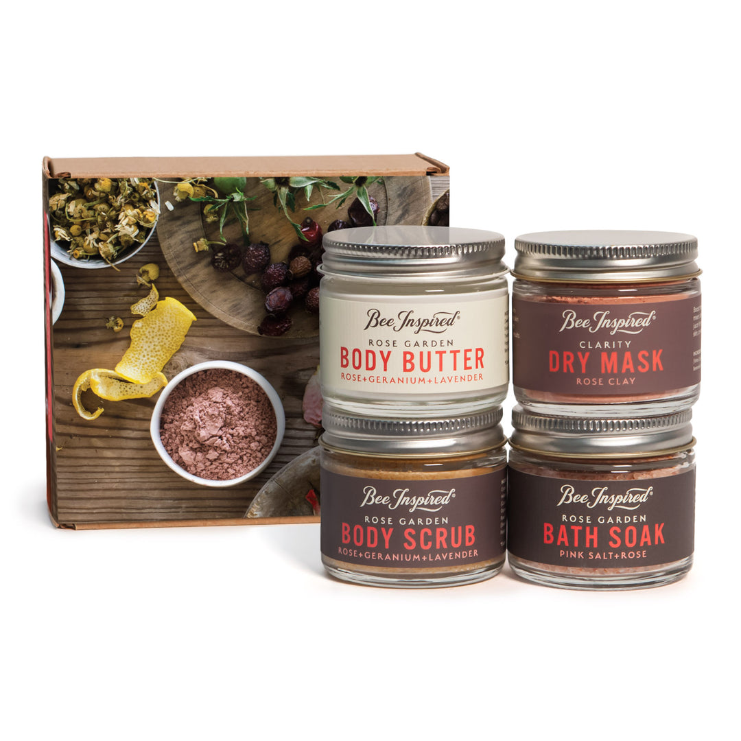 Set of Bee Inspired skin care products including body butter, dry mask, body scrub, and bath soak with a wooden box in the background.