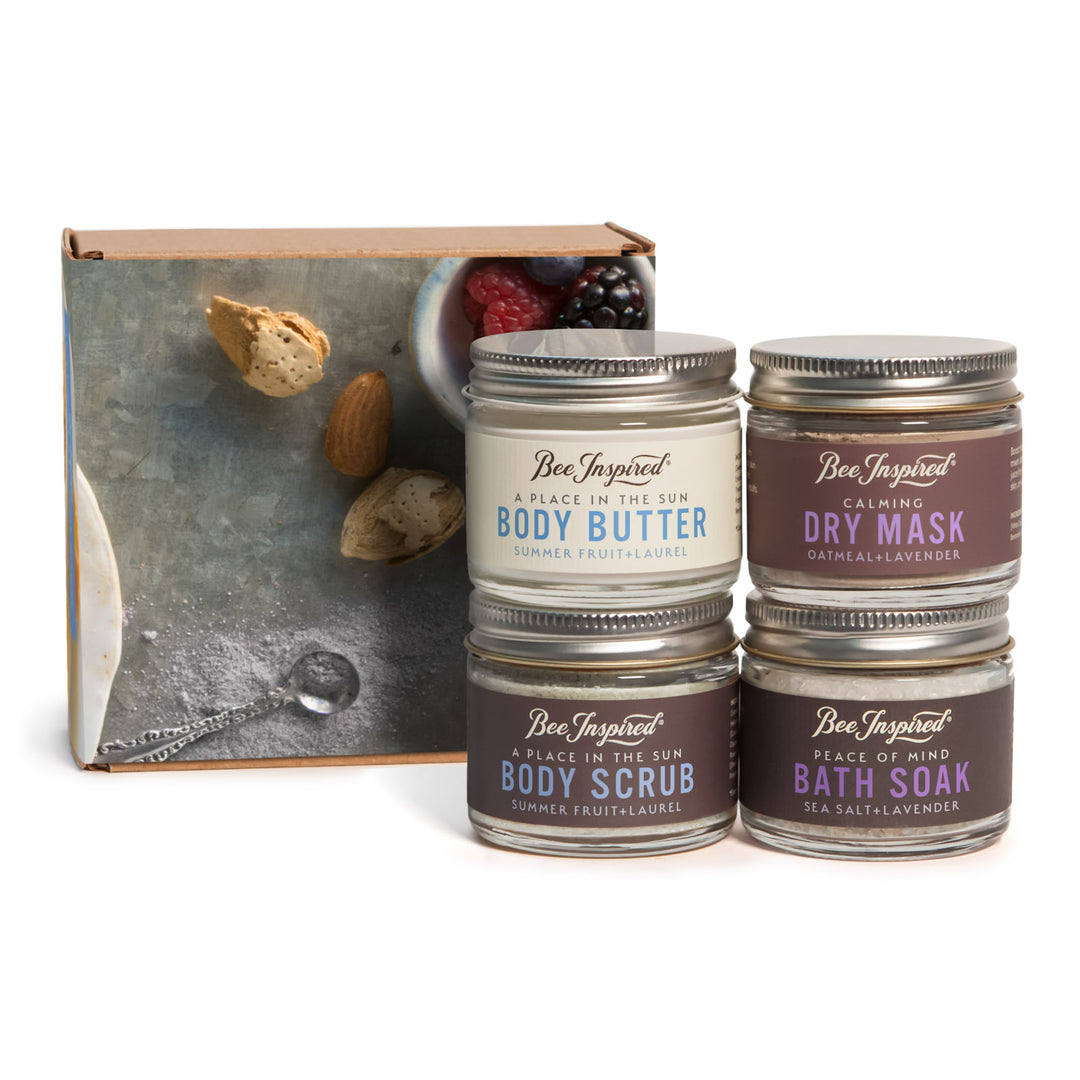 Set of Bee Inspired body care products including body butter, dry mask, and bath soak in front of a decorative box.