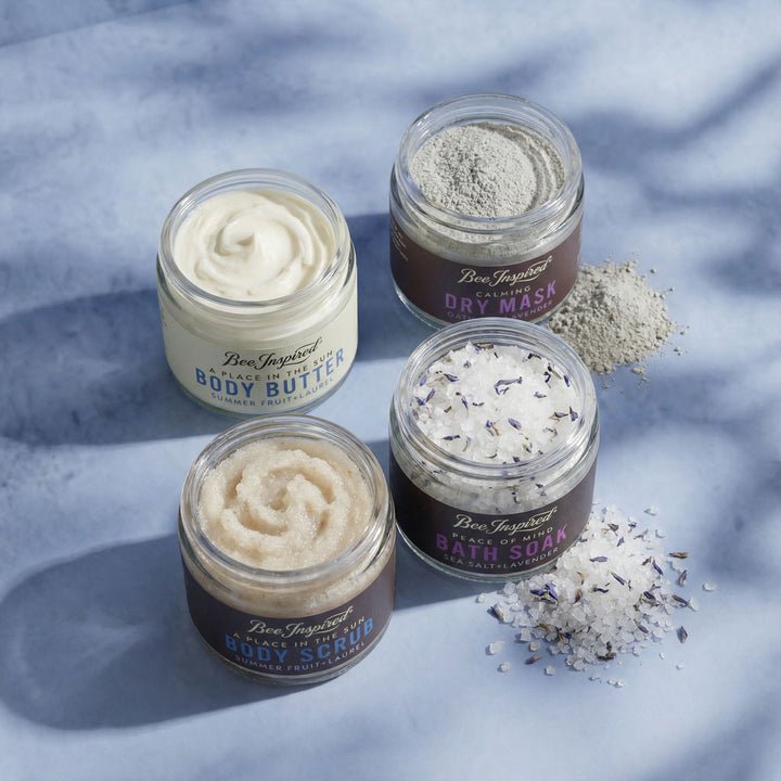Four jars of body care products on a textured blue surface