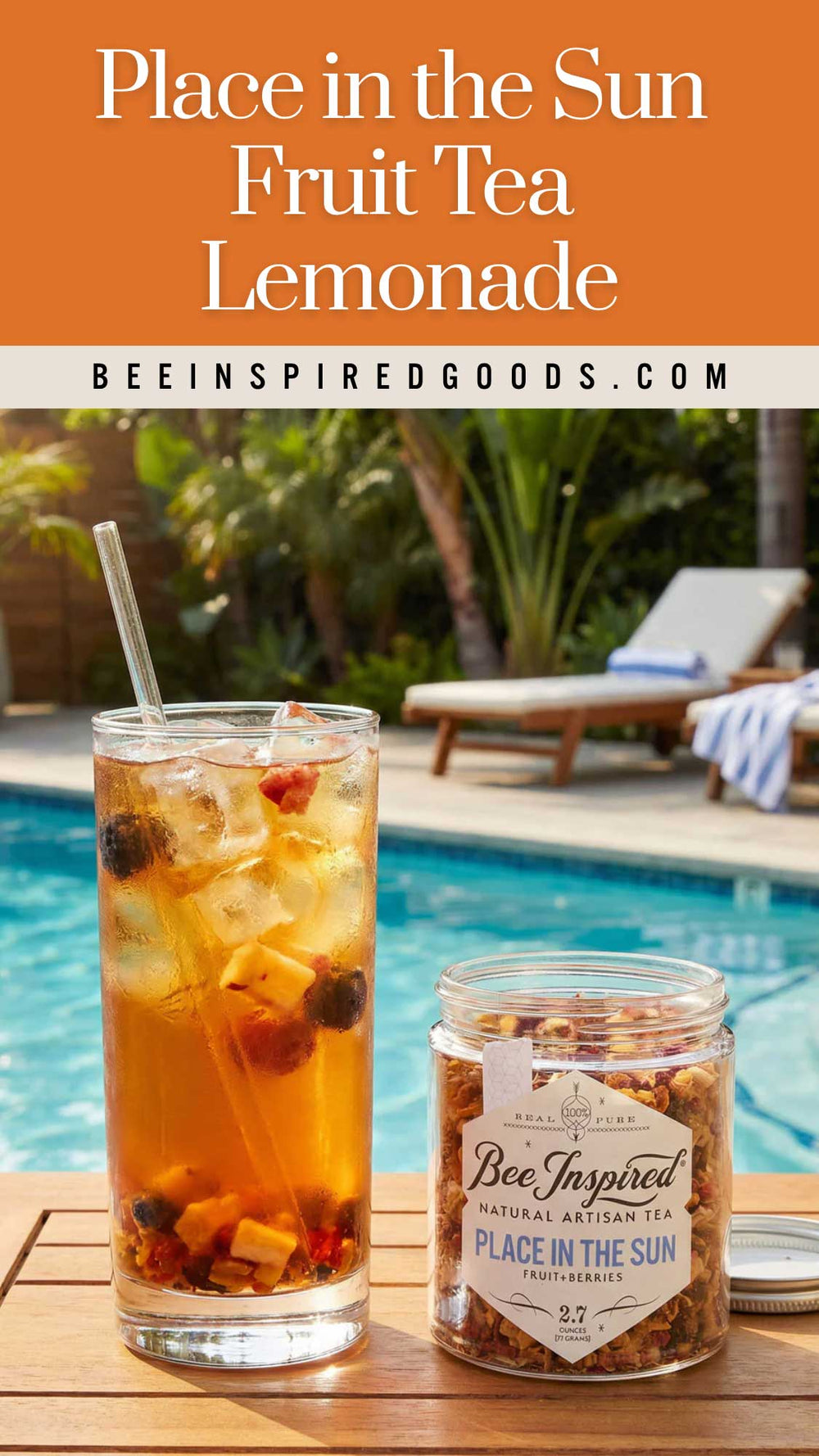 A glass of iced fruit tea lemonade and a jar of Bee Inspired Goods Place in the Sun natural artisan tea sit on a wooden table next to a swimming pool with lounge chairs in the background.
