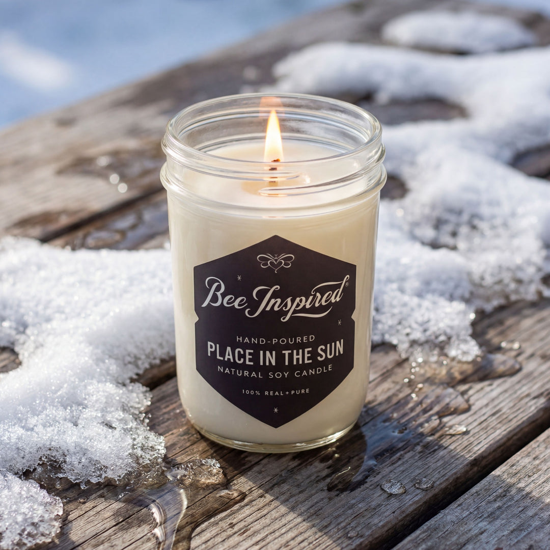 Candle in a jar labeled 'Bee Inspired' on a snowy surface