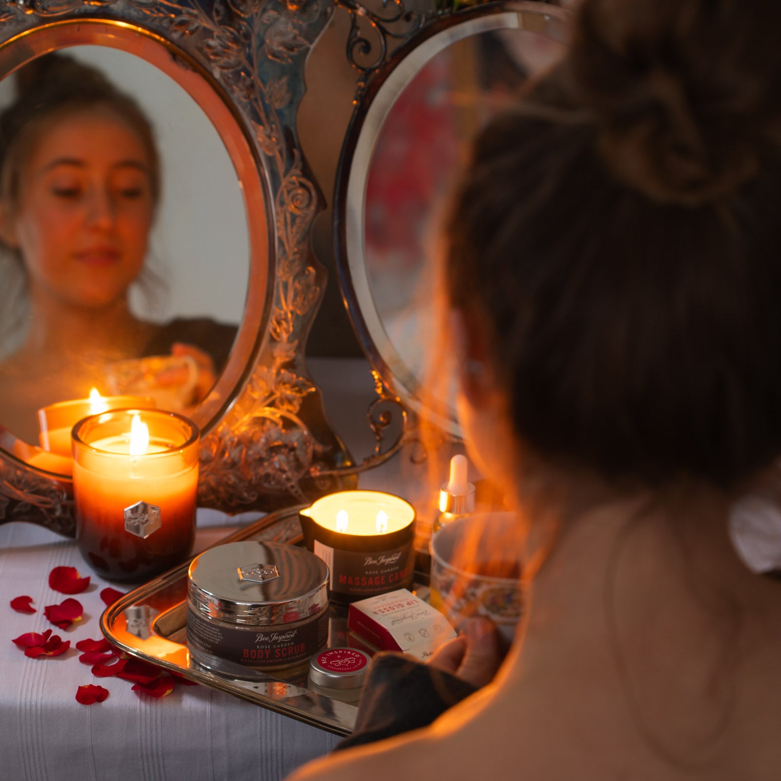 woman looks at Rose Garden products and burning candle in front of mirror