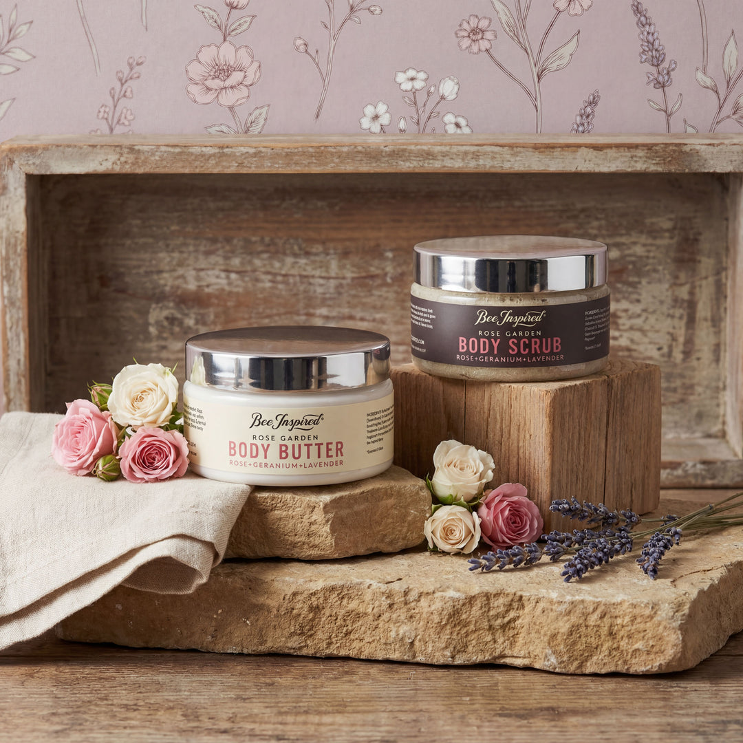 Two jars of Bee Inspired body products on a wooden shelf with flowers and a floral-patterned wall.