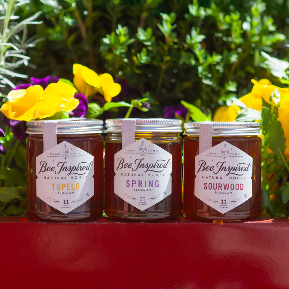 Three jars of 'Bee Inspired' honey with floral background