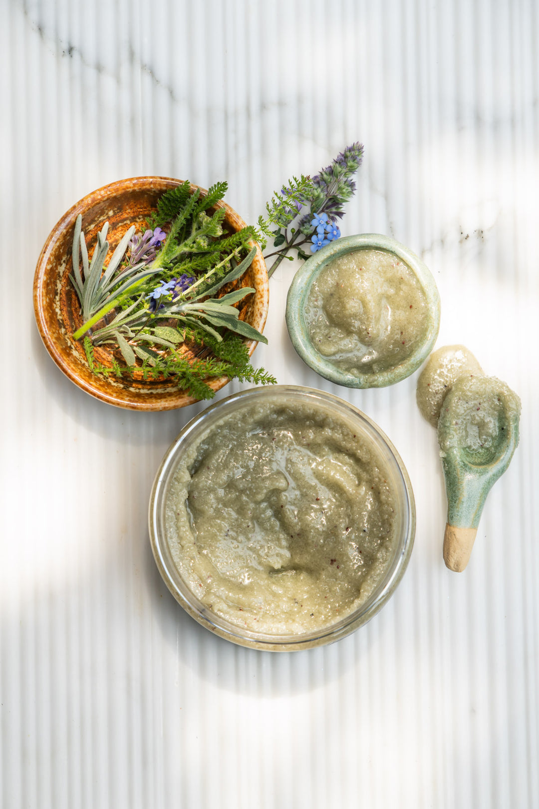 sea+tea scrub next to a small bowl filled with scrub and another small bowl filled with greenery