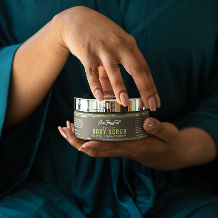 Person holding a jar of 'Body Scrub' with a dark background