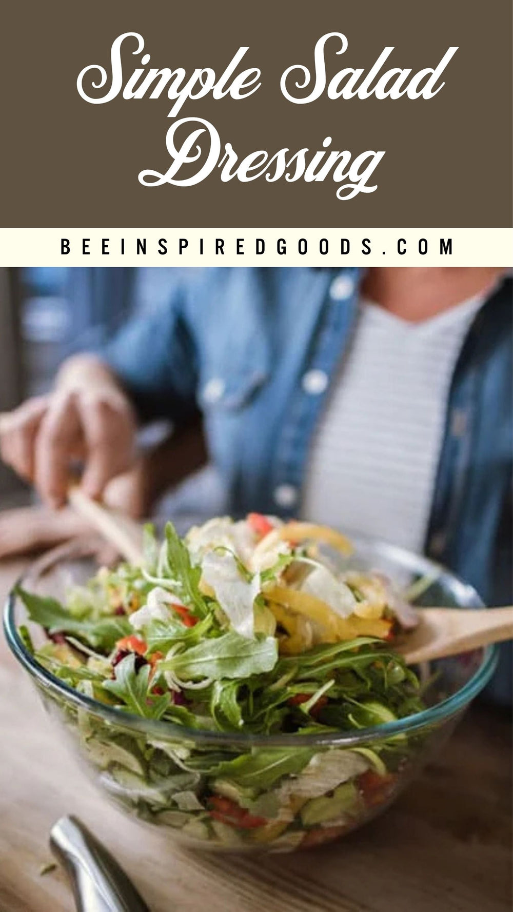 A glass bowl filled with a green salad on a wooden table, with a person in a blue denim shirt tossing the salad. The top of the image features a brown banner with white text reading 'Simple Salad Dressing' and 'BEEINSPIREDGOODS.