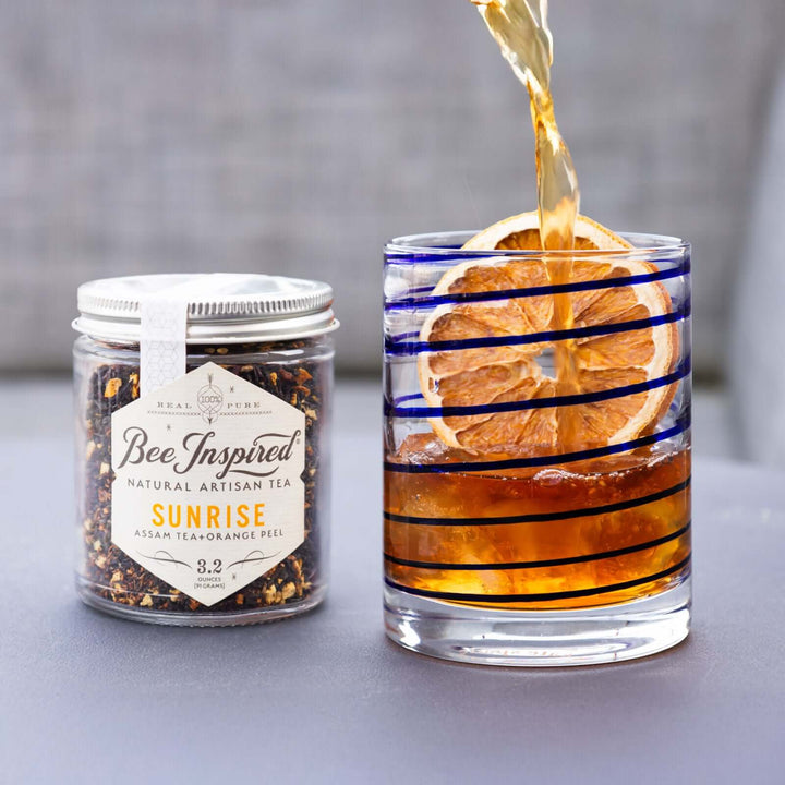 pouring a glass of iced Sunrise Assam tea garnished with a dried orange slice