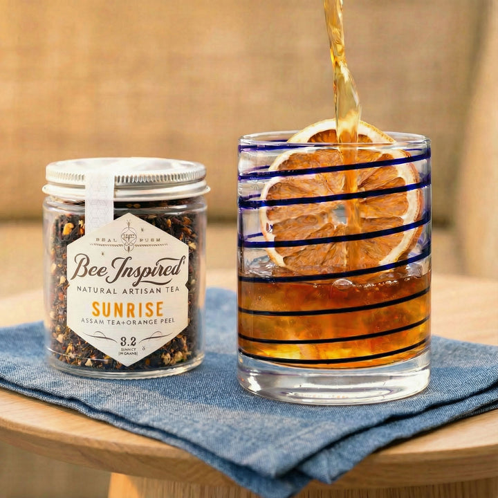 Bee Inspired tea jar with a glass of iced tea on a wooden table