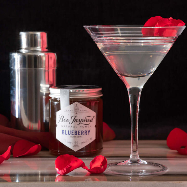 blueberry honey from bee inspired honey retail store in owings mills next to a martini glass with rose petals