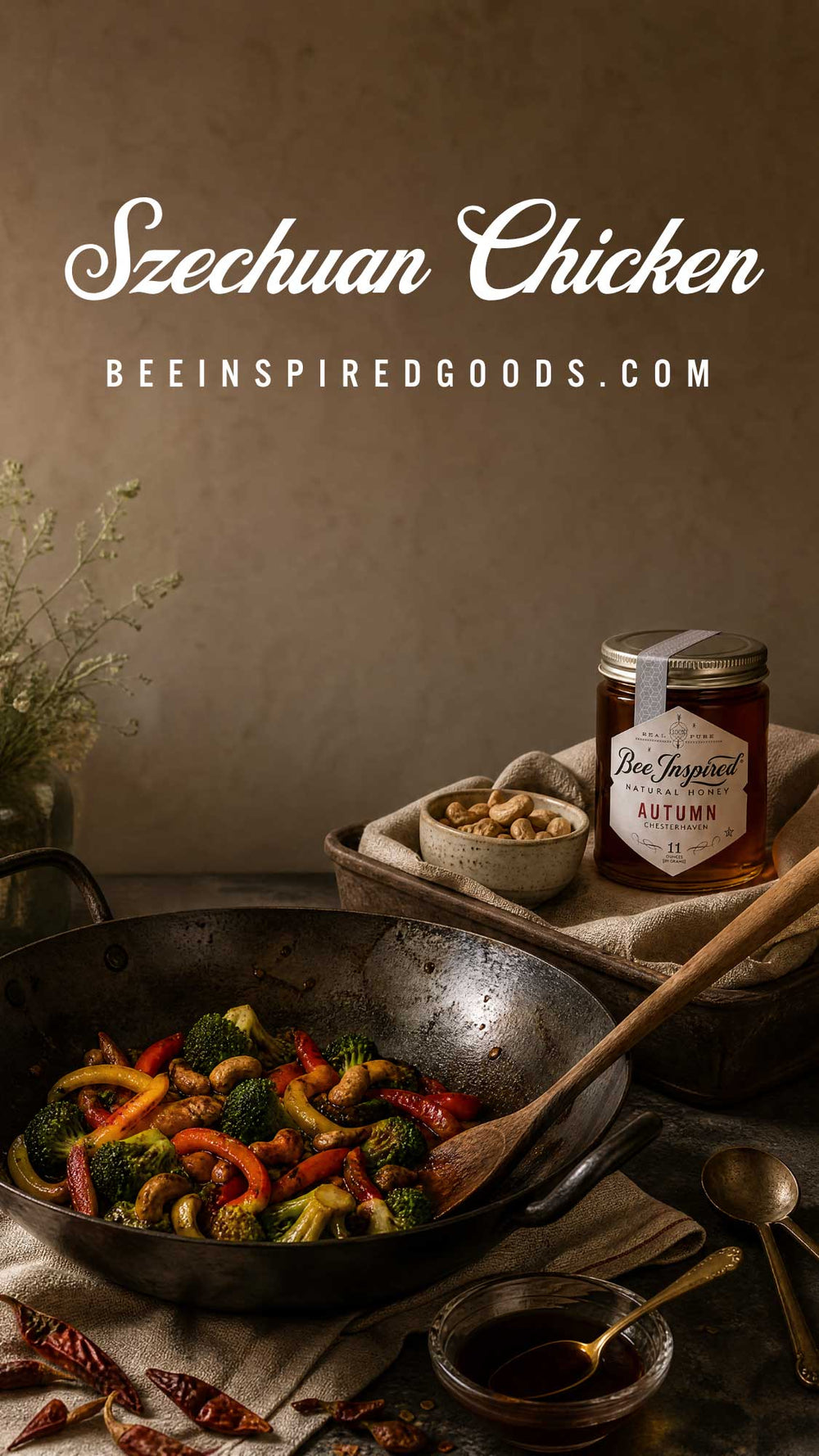 A styled food scene featuring a dark metal wok filled with colorful stir-fried vegetables, including broccoli, red peppers, and carrots, with a wooden spoon resting inside. In the background, a jar labeled 'Bees Inspired Goods Autumn' sits on a tray next to small bowls of ingredients.