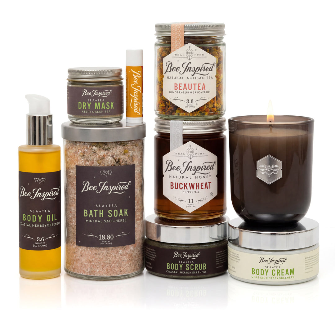 Collection of Bee Inspired beauty products including candles, oils, and scrubs on a white background.
