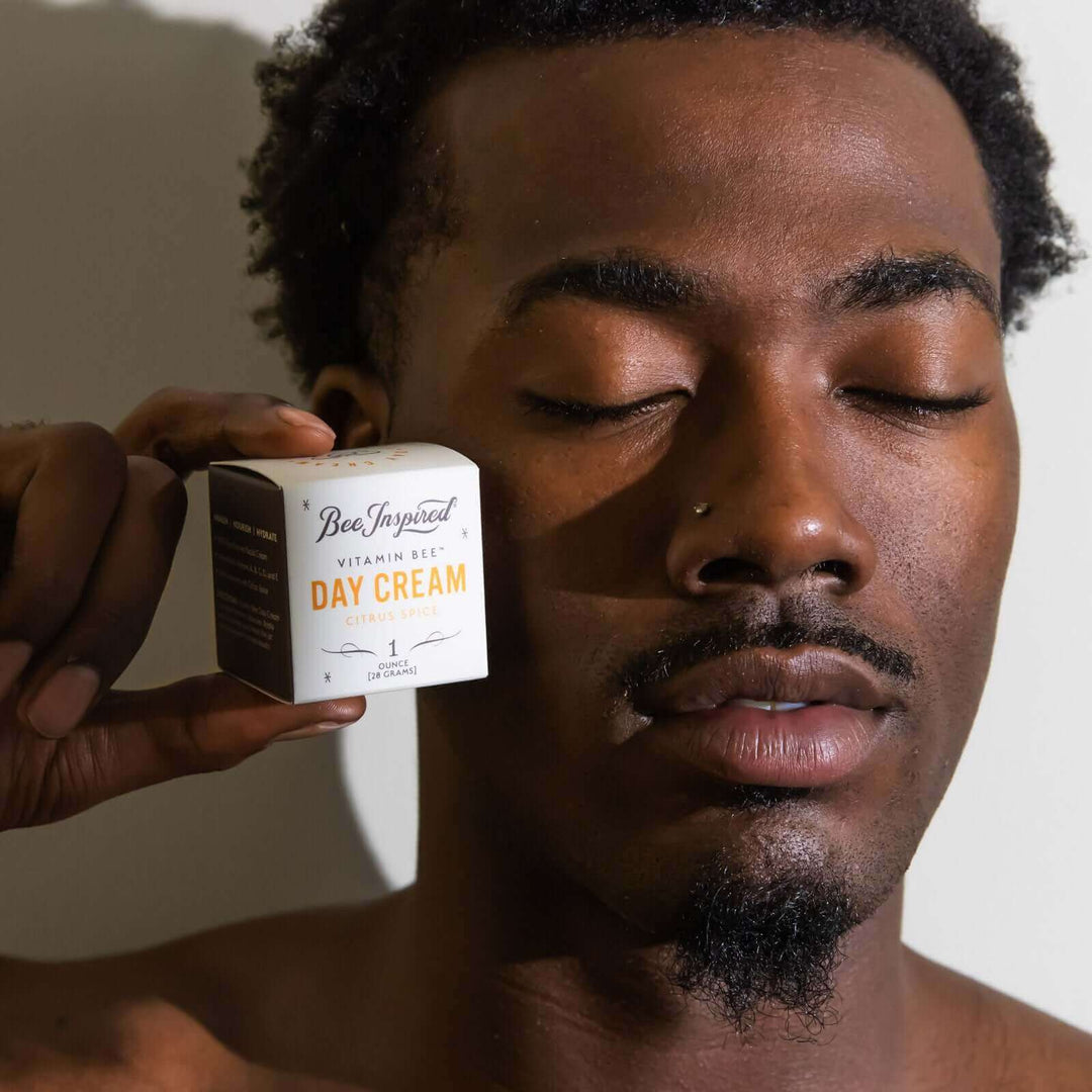 man holds Vitamin Bee citrus spice day cream by his face