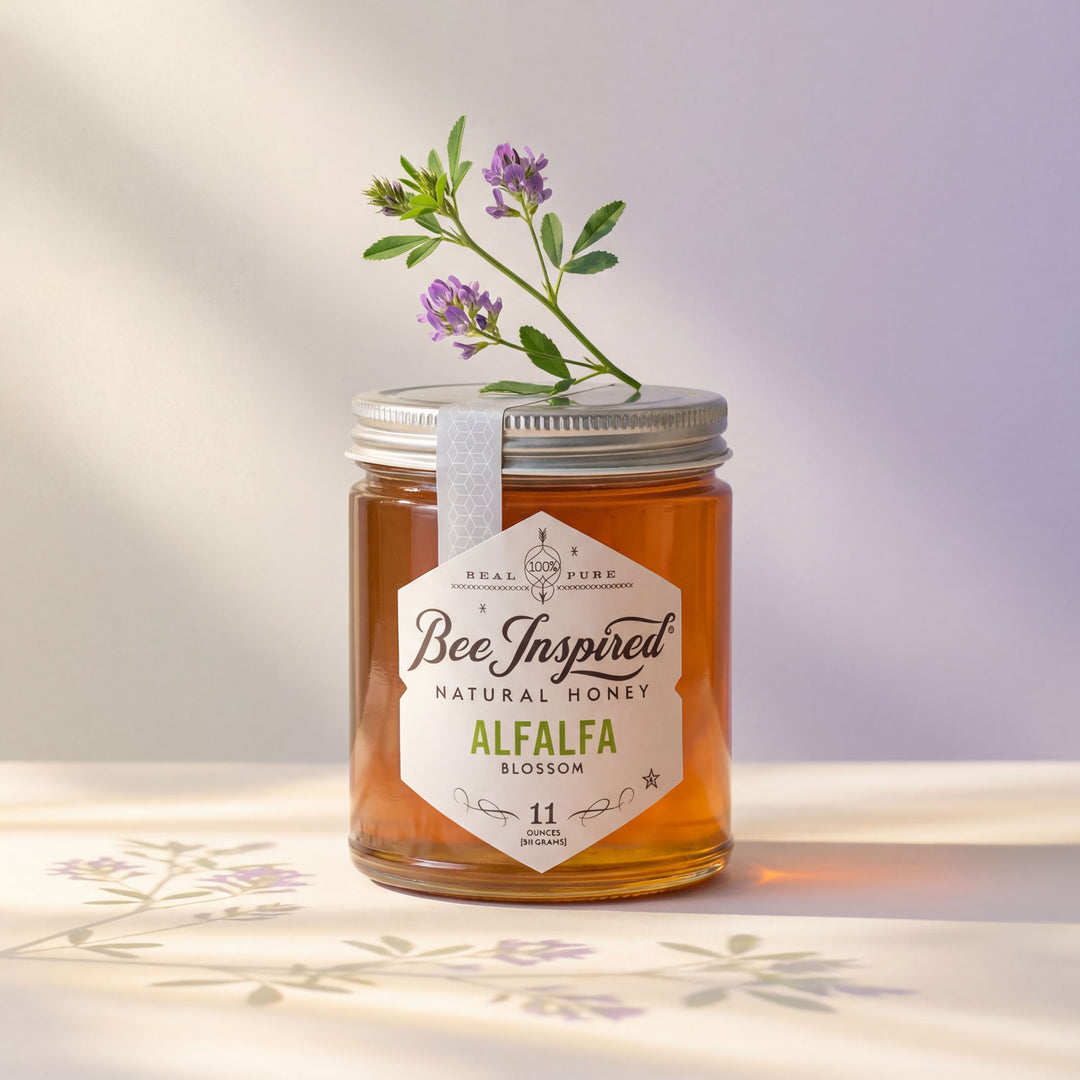 Jar of 'Bee Inspired' natural honey with a label and a sprig of alfalfa on a light background